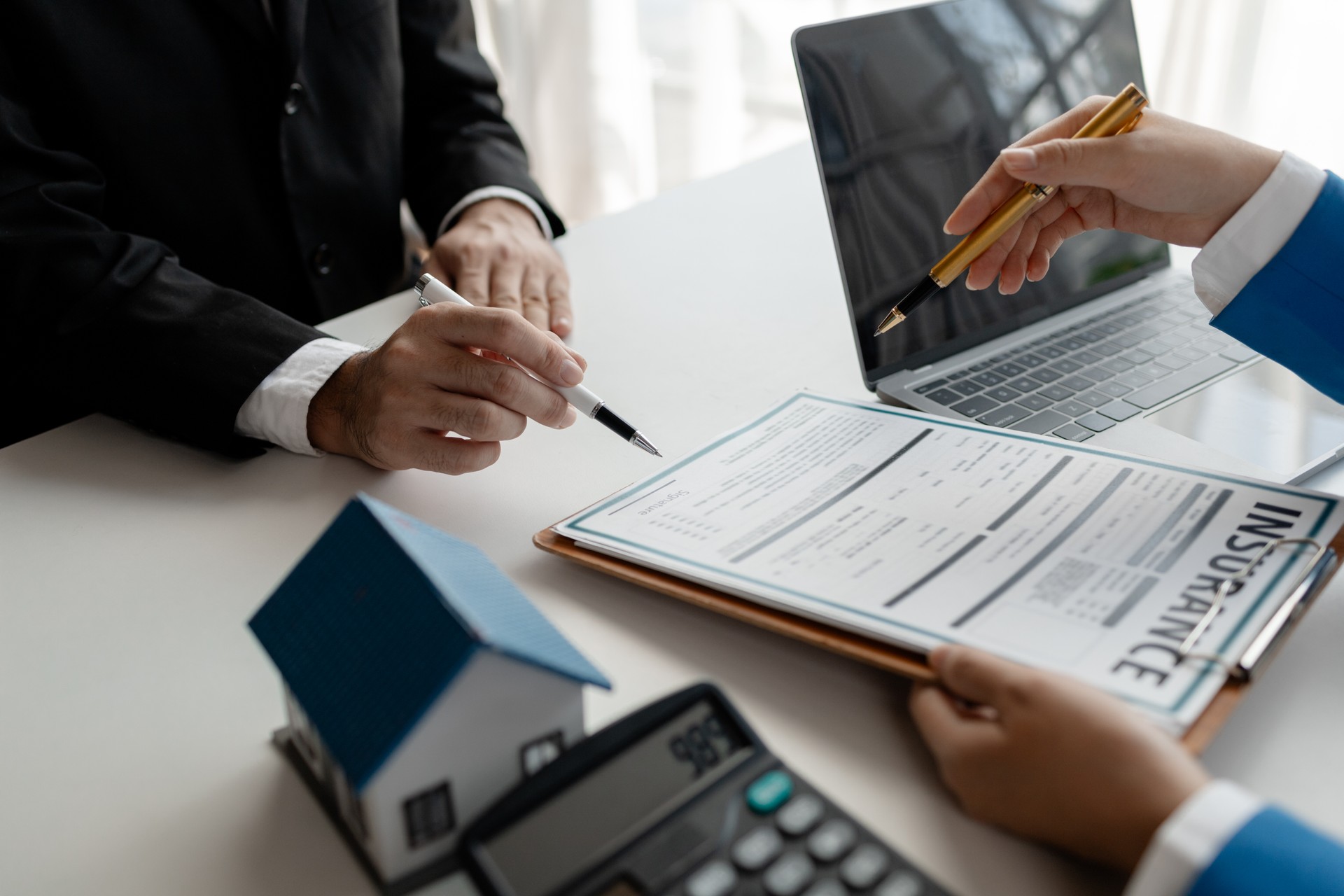 House insurance paperwork, A real estate agent is explaining home insurance documents to a buyer in his office at the company, Sign home insurance documents, make an agreement together.